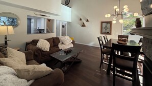 A spacious living area with a brown sofa, a dining table with chairs, a coffee table, and a fireplace. - Cottonwood Chalet - New Remodel - Private Hot Tub 3BR/2BA + 4 Ski Resorts (Cottonwood Heights)