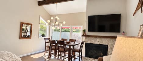 Una sala de estar con chimenea, un comedor y un televisor montado en la pared.