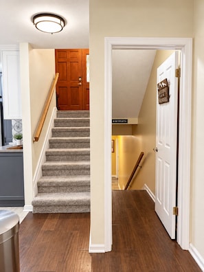 A staircase with a wooden handrail leading to a door with a 'Welcome to the Mountains' sign.