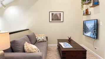 A living room with a sofa, a coffee table, a TV, and a framed picture on the wall.