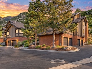 A residential area with two houses, a driveway, and a mountain backdrop.