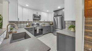 A modern kitchen with white cabinets, stainless steel appliances, and a patterned backsplash. - Cottonwood Chalet - New Remodel - Private Hot Tub 3BR/2BA + 4 Ski Resorts (Cottonwood Heights)