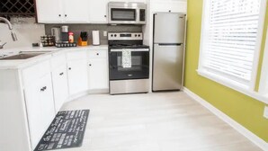 Cocina moderna con armarios blancos, electrodomésticos de acero inoxidable y encimera negra.