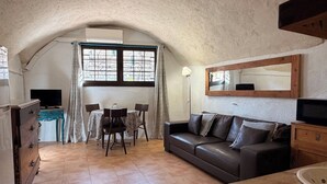 Una stanza accogliente con un tavolo da pranzo, sedie, un divano, una TV e uno specchio.