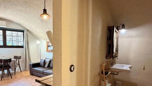 Una stanza con un tavolo di legno, un divano, una finestra vista e un lavandino con uno specchio.