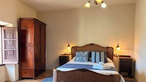 A bedroom with a large bed, two bedside tables, a wooden wardrobe, a rattan headboard, and a hanging light fixture. - L'Escala-Ventalló. Cosy, WiFi & Rooftop terrace EG (Ventalló)