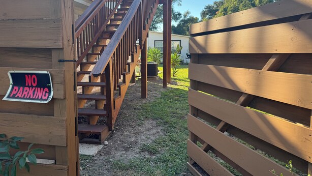 Un escalier en bois mène à une terrasse où est affiché un panneau indiquant « INTERDICTION DE STATIONNER ».