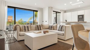 A modern living room with a sectional sofa, a coffee table, and a dining area. - Luxury Mirador Resort Apartment (Estepona)