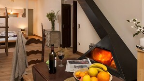 A cozy living room with a wood-burning stove, a dining table with a bowl of fruit, a wine bottle, and a newspaper. - Acollidor i tranquil.L'Empordà -10m l'Escala.EP (Ventalló)