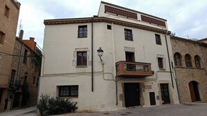 Un edificio de varios pisos con un balcón, una farola y un cartel que indica que es un establecimiento.