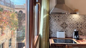 Una cocina con estufa, tostadora y cafetera, una ventana con cortina y un salpicadero decorativo.