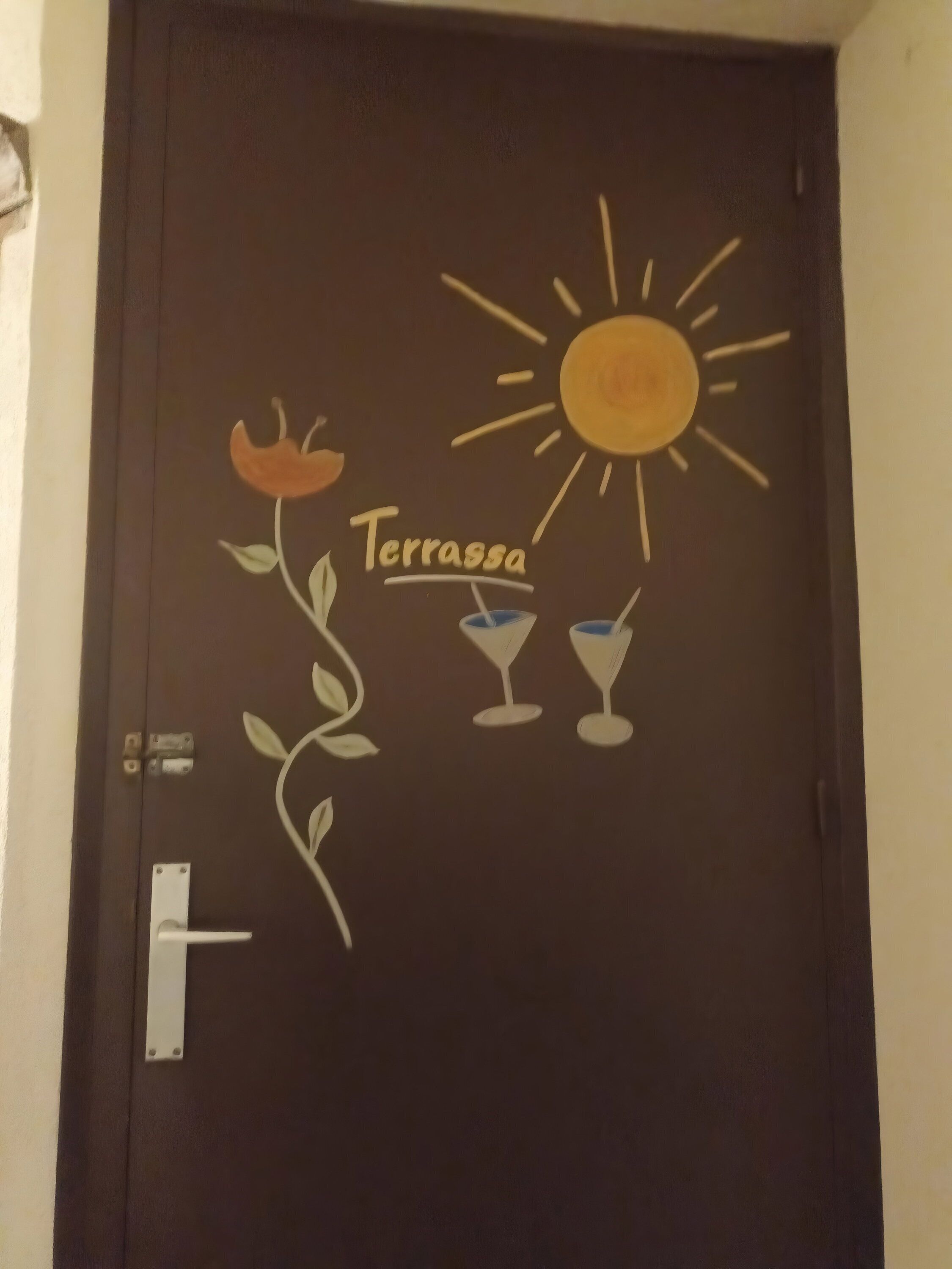 A door with a drawing of a sun, a flower, and two drinks labeled 'Terrassa'.