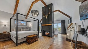Een ruime slaapkamer met een hemelbed, een open haard en een groot raam.