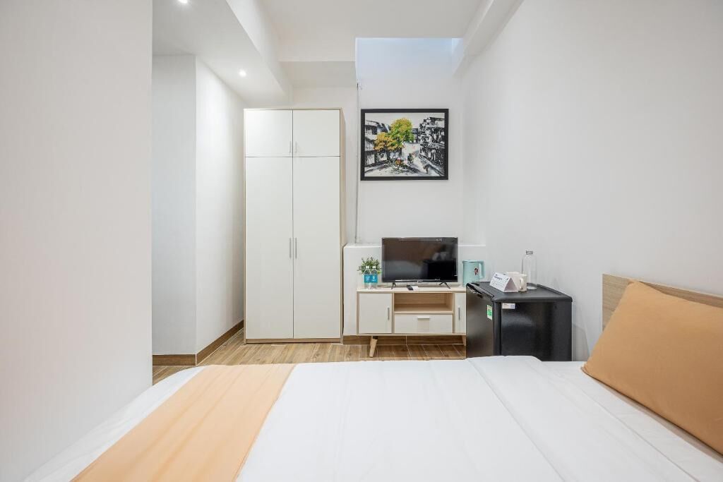 A hotel room with a bed, a TV, a desk, and a wardrobe.
