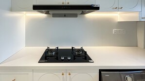 Una cocina moderna con armarios blancos, una placa de cocina negra e iluminación debajo de los armarios.