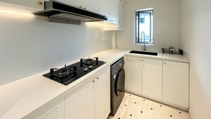 Una cocina compacta equipada con estufa a gas, lavavajillas y un ventanal que proporciona luz natural.