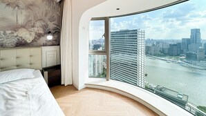 A modern bedroom with a curved window offering a city view. - Book and Bed-Weifang Store (Shanghai)
