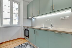 A modern kitchen with light green cabinets, a stainless steel sink, and a built-in oven. - Royal View Suite - Corfu Town (Corfu)
