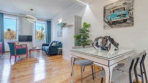 A modern living room with a glass dining table, blue sofa, and a large window. - Royal View Suite - Corfu Town (Corfu)