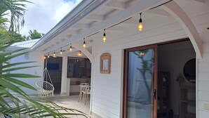 A covered outdoor area with string lights, a sliding glass door, and a white exterior wall. - The Colibri, Orient Bay, Private Jacuzzi (ST MARTIN)