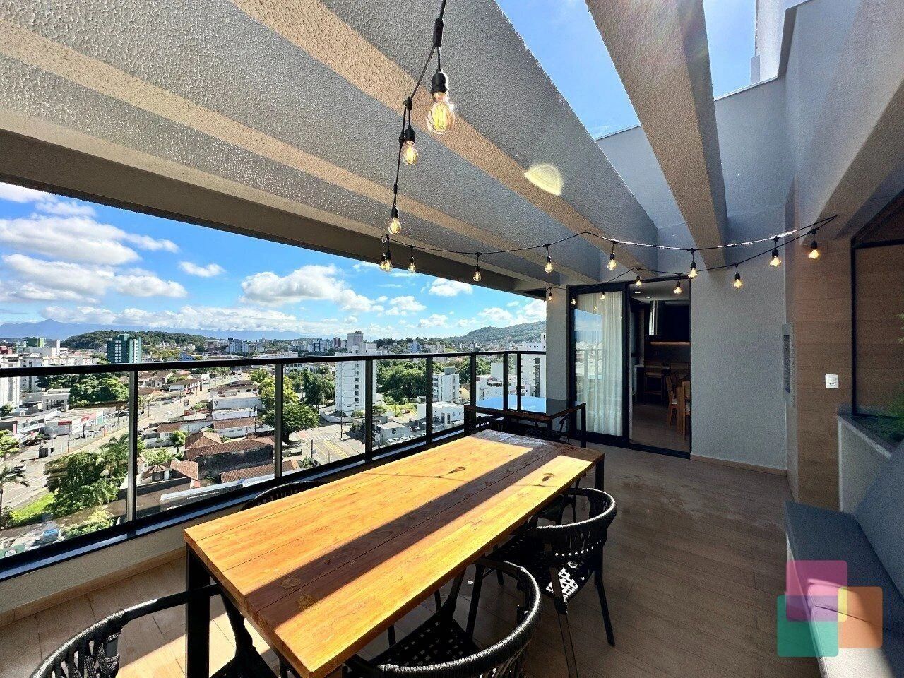 Un balcón con una mesa y sillas de madera, con vista a un paisaje urbano.