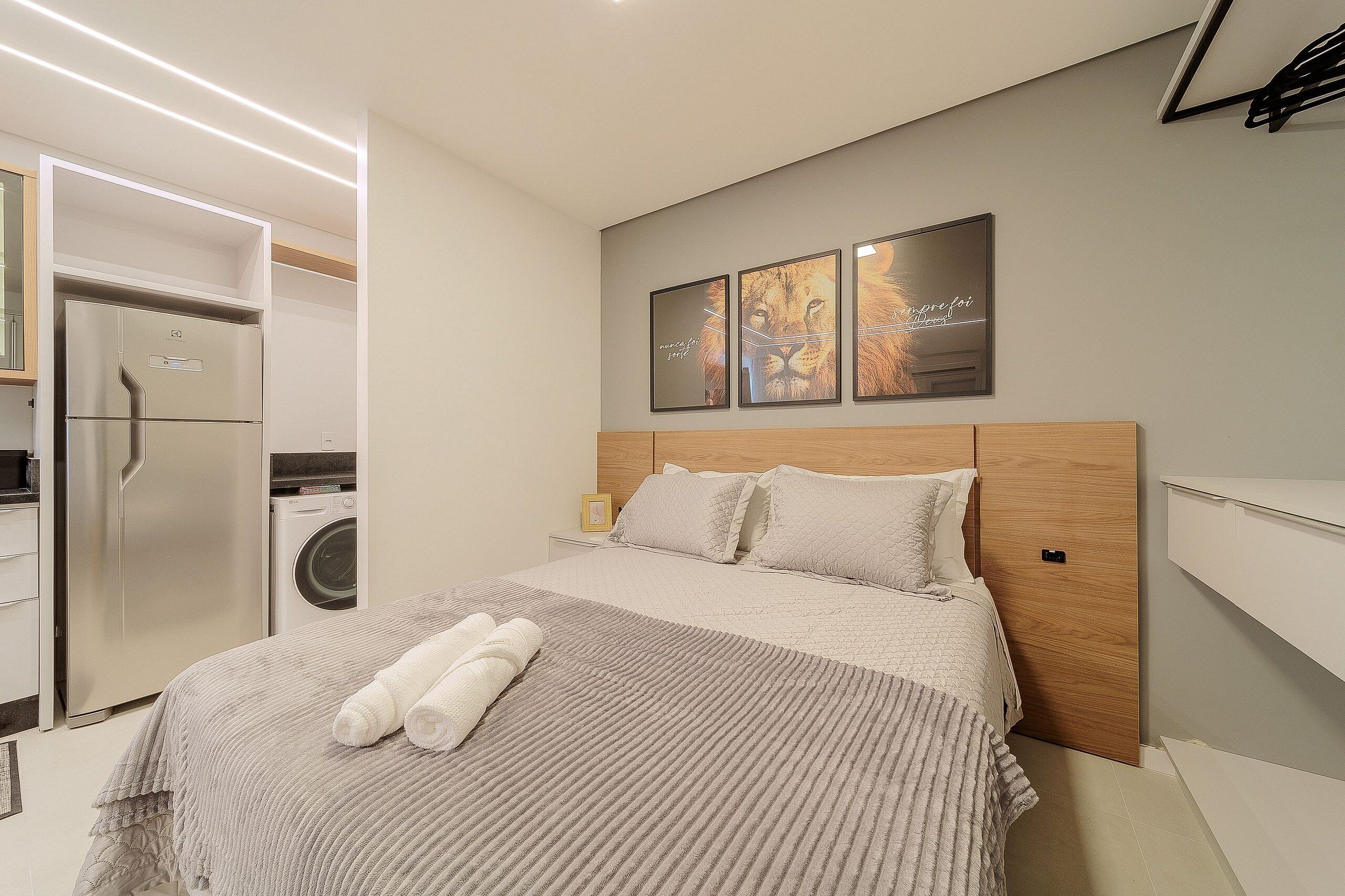 Quarto de hotel moderno com uma cama, máquina de lavar e frigorífico.
