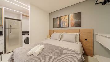 Quarto de hotel moderno com uma cama, máquina de lavar e frigorífico.