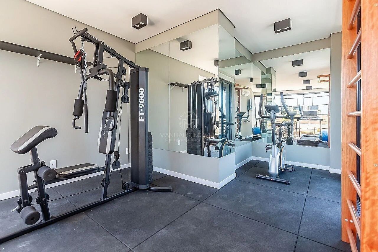 Ein modernes Fitnessstudio mit verschiedenen Trainingsgeräten, darunter eine Hantelbank, ein Squat-Gestell und ein Spiegel, der den Raum wiedergibt.