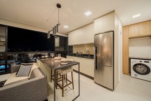 A modern kitchen with a central island, stainless steel appliances, and a built-in washer and dryer. - Studio H Residencial Flipchave STH000 (Joinville)