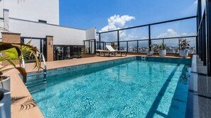 A rooftop swimming pool with clear blue water, lounge chairs, and potted plants. - Studio H Residencial Flipchave STH000 (Joinville)