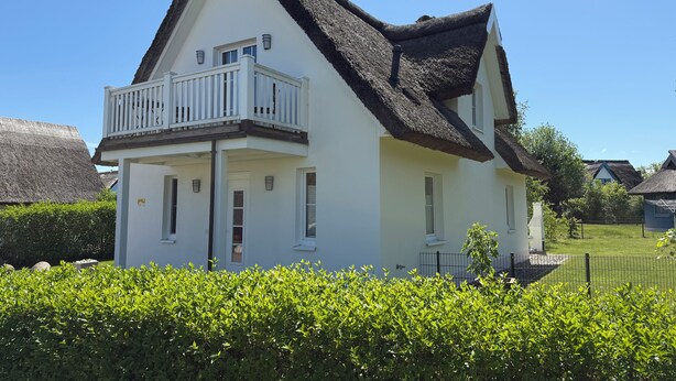 A two-story house with a thatched roof and a balcony.