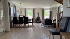 A spacious living room with a dining area, a fireplace, and large windows.