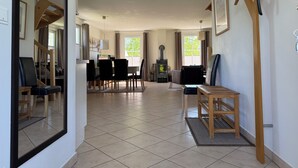 A spacious living area with a dining table, chairs, a sofa, a fireplace, and a coat rack.