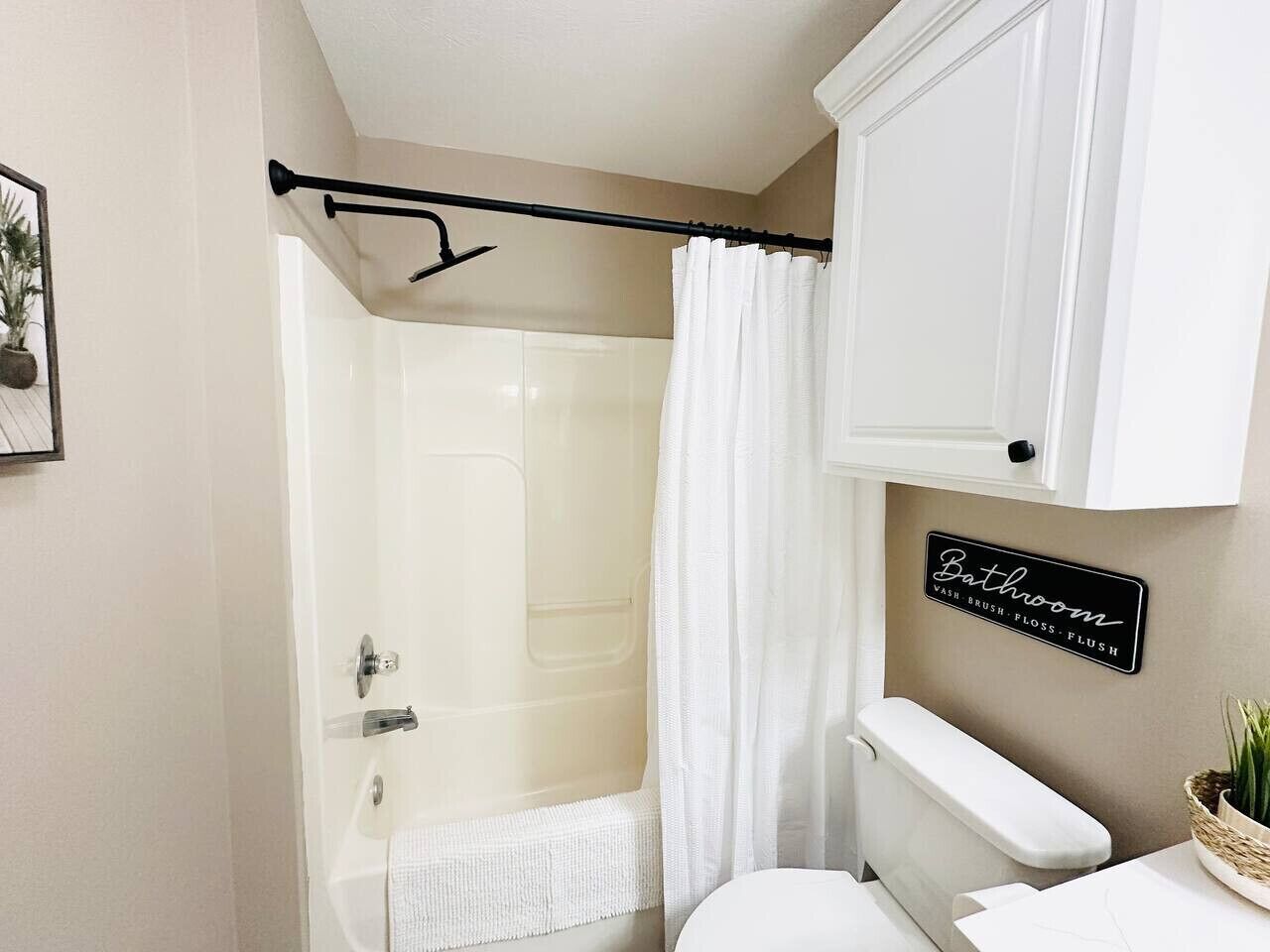 Een badkamer met douche, toilet en een bord aan de muur.