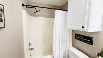 Een badkamer met douche, toilet en een bord aan de muur.