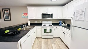 Une cuisine moderne avec des meubles blancs, un four à micro-ondes, une cuisinière et un réfrigérateur.
