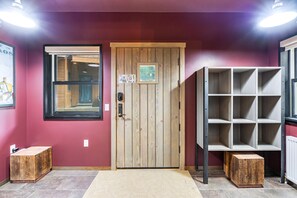 A wooden door with a small picture, a window, and a shelf unit.