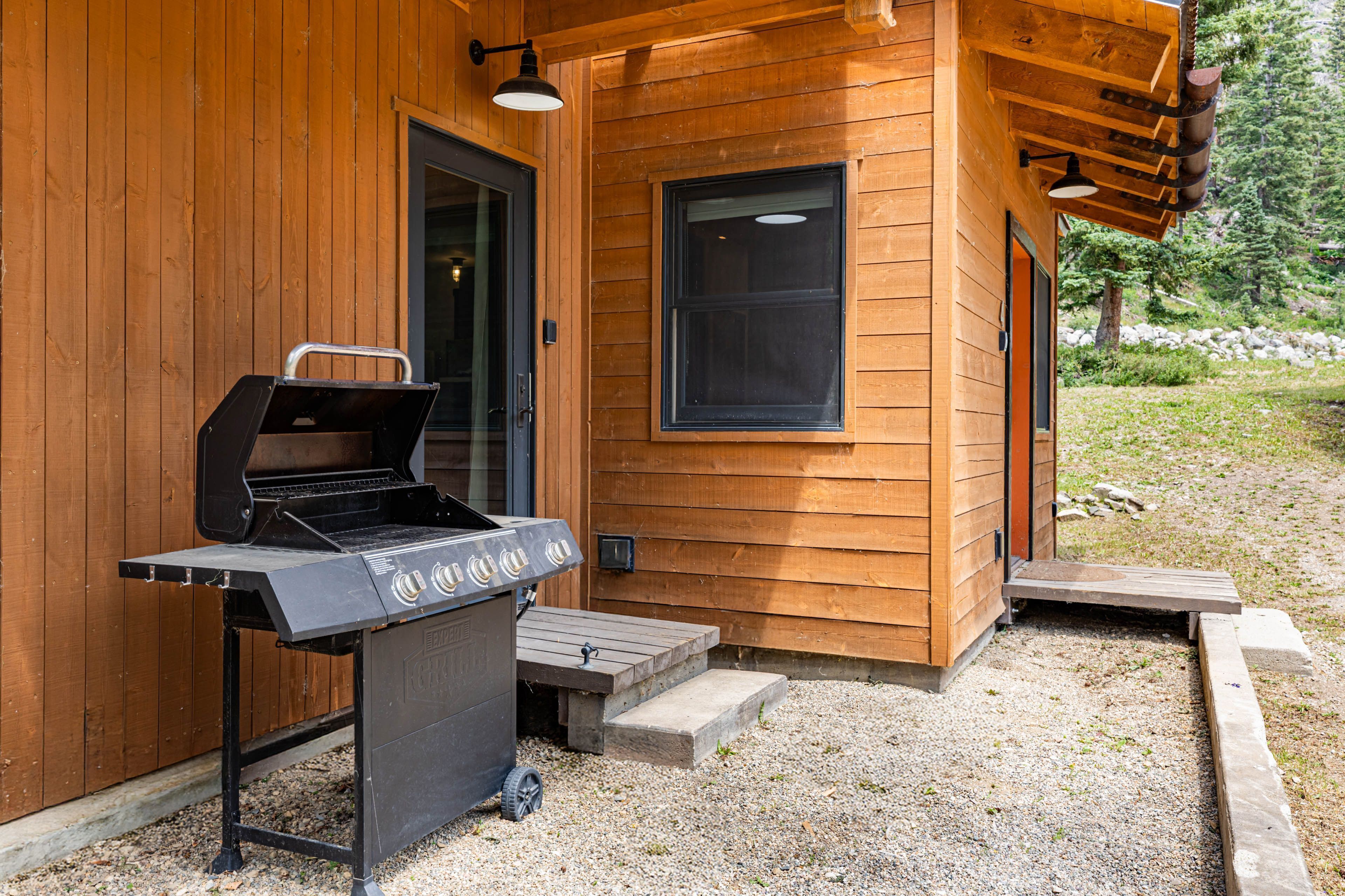 Een houten hutje met een barbecue buiten.