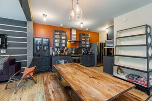 A modern kitchen with a wooden dining table, built-in cabinets, and a bookshelf.