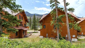 A wooden cabin with a sloped roof, surrounded by trees and a mountainous backdrop. - Bavarian Chalet - Ski-In Ski-Out Taos Ski Valley (Taos Ski Valley)