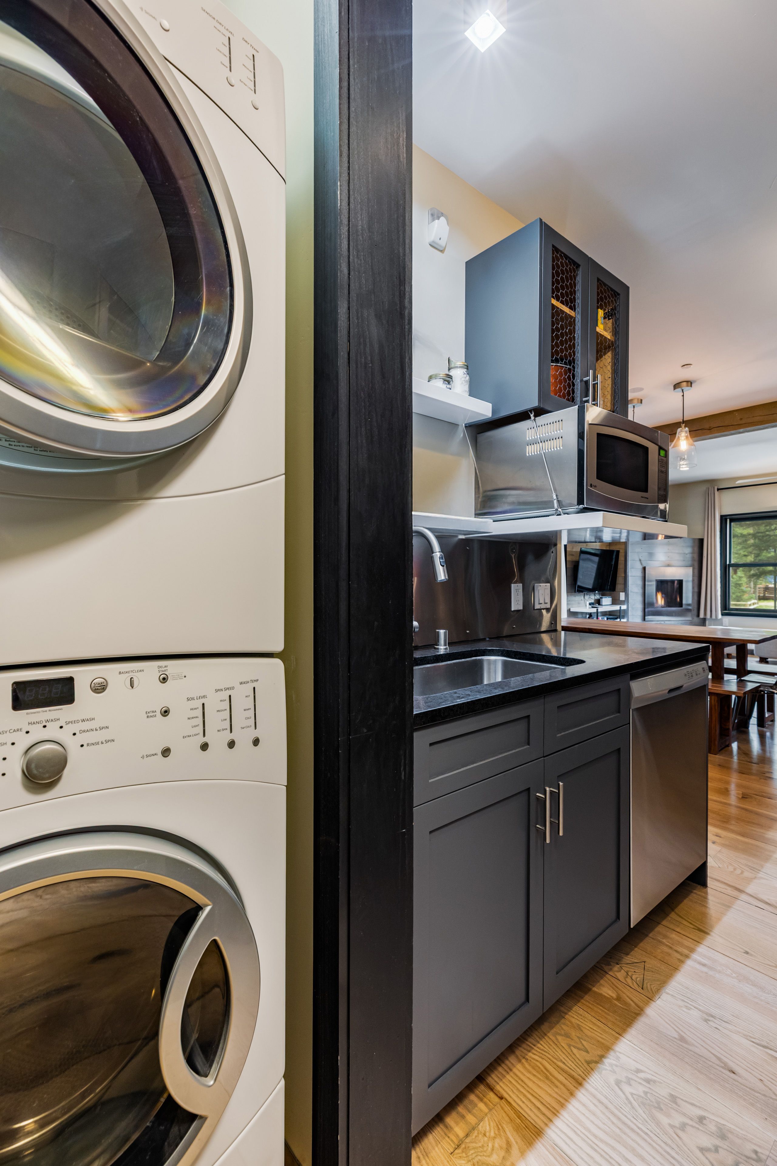 Une cuisine compacte équipée d’un lave-linge et d’un sèche-linge intégrés, d’un four à micro-ondes et d’un petit coin repas.