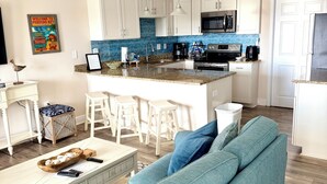 Una cucina moderna con mobili bianchi, un'isola centrale e una ventola a soffitto.