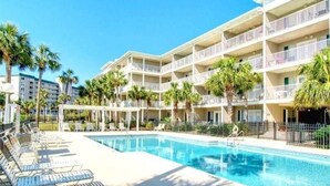 Un hotel con piscina, numerosi balconi e palme.