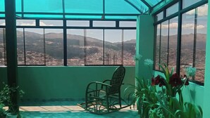 Um alpendre coberto com vista para uma paisagem urbana e montanhas.