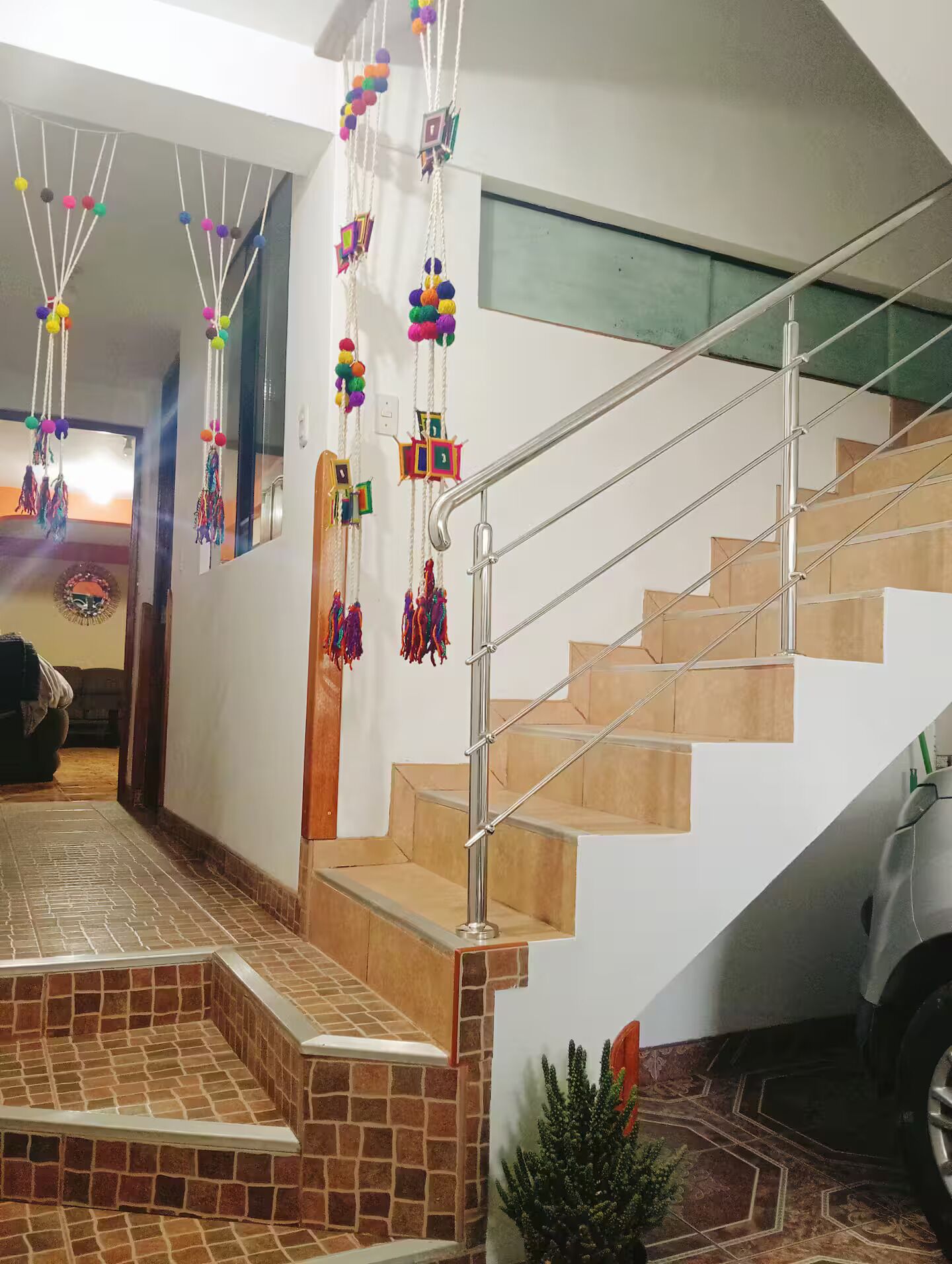 A staircase with a metal railing, a tiled floor, and decorative hanging ornaments.