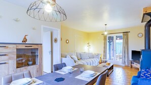 Un salon moderne avec un coin repas, un plancher en bois et une grande fenêtre.