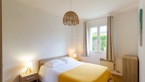 Une chambre à coucher avec un lit, une table de chevet, une lampe et une fenêtre avec des rideaux.