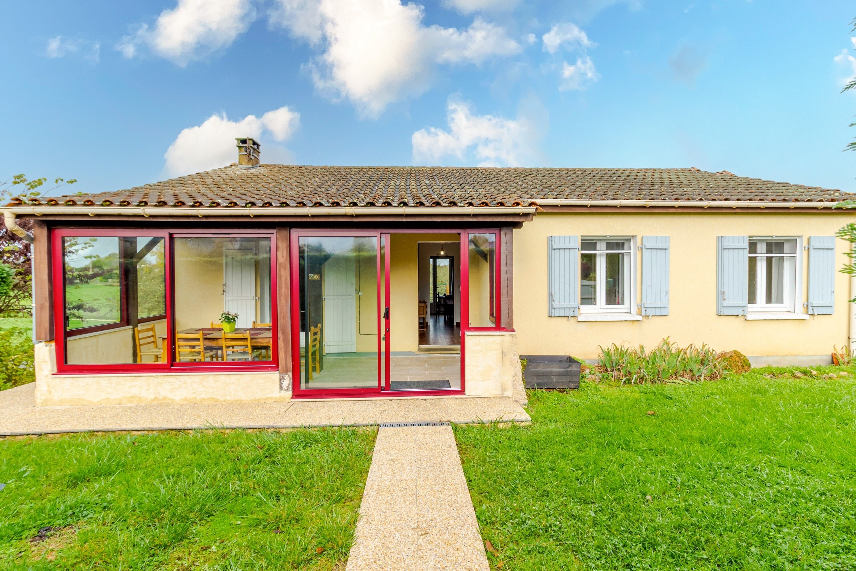 A single-story house with a tiled roof, large glass doors, and a small porch.