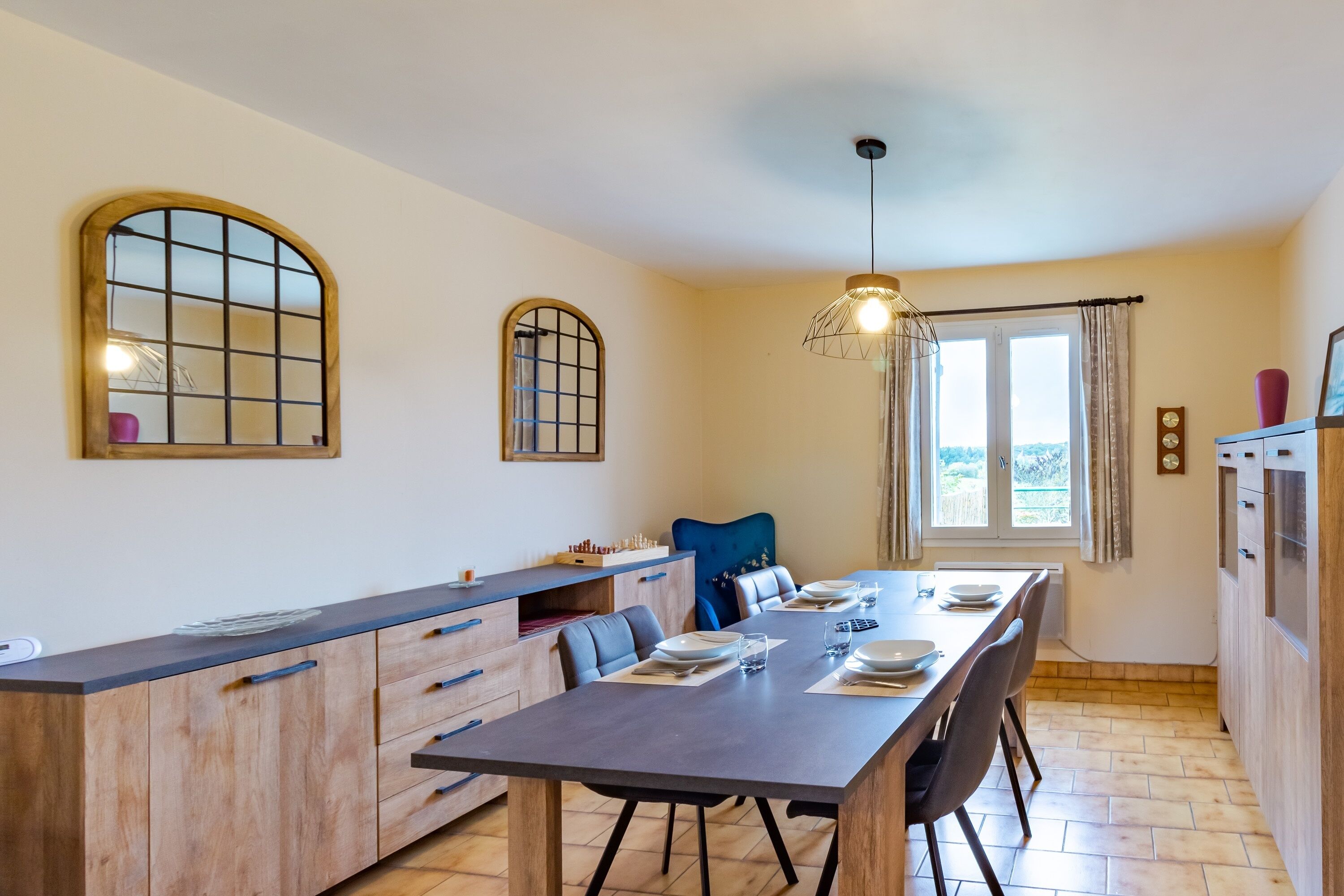 Una cucina moderna con zona pranzo, mobili in legno, una panca integrata e un'ampia finestra con tende.