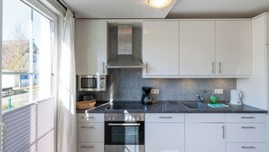 Une cuisine moderne avec des armoires blanches, une hotte de cuisinière en acier inoxydable, un four à micro-ondes et un four encastré.